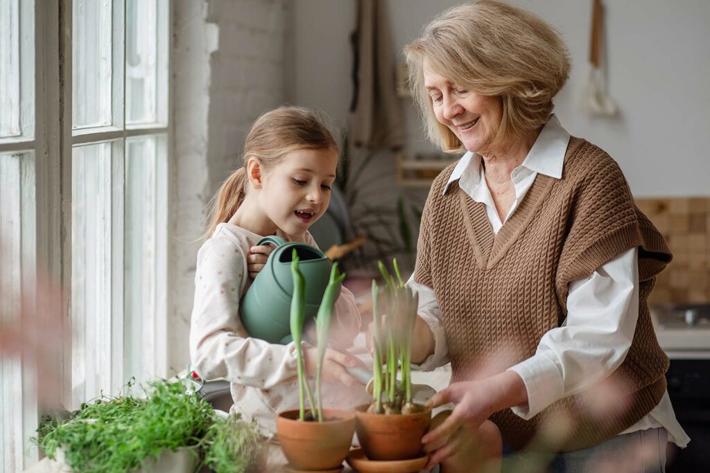 Oma und Enkelin gießen gemeinsam eine Pflanze