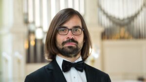 Porträtbild Professor Pohle: Junger Mann mit halblangem Haar, Brille, Vollbart.