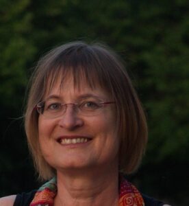 Frau mit Brille vor grünem Busch