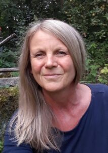 Frau mit langen Haaren vor grüner Pflanzenwand