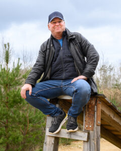 Ein mann sitzt auf einem Zaun.