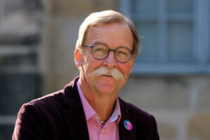 Man sieht einen Mann mit Schnauzbart.