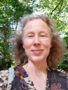 lachenden Frau mit blondem Haar vor Bäumen