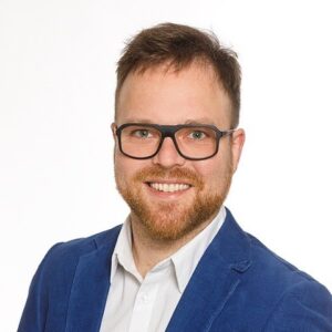 Mann mit Brille und blauem Anzug der lacht