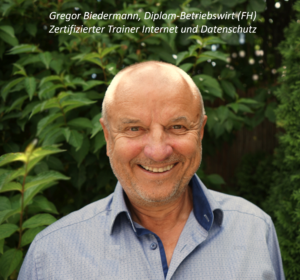 Man einen Mann lächelns vor einer Hecke stehen. Es ist ein Foto Gregor Biedermann.