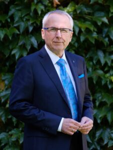 Mann mit Brille und Anzug vor Efeu
